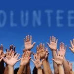 volunteer-group-raising-hands-sky-cloud