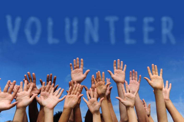 volunteer-group-raising-hands-sky-cloud